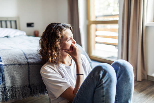 Anxious women sits at the foot of her bed.